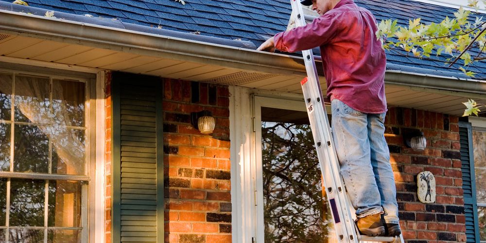 Man,Cleaning,Gutters,On,Ladder